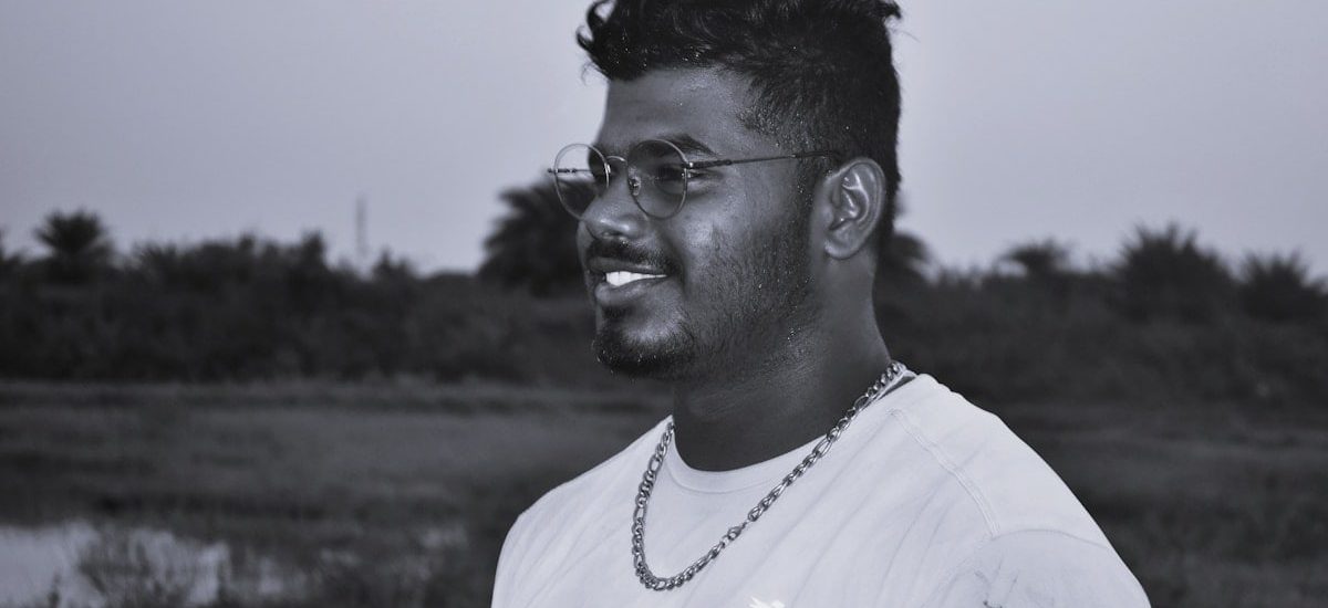a man with glasses standing in a field