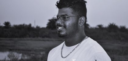 a man with glasses standing in a field