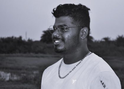 a man with glasses standing in a field